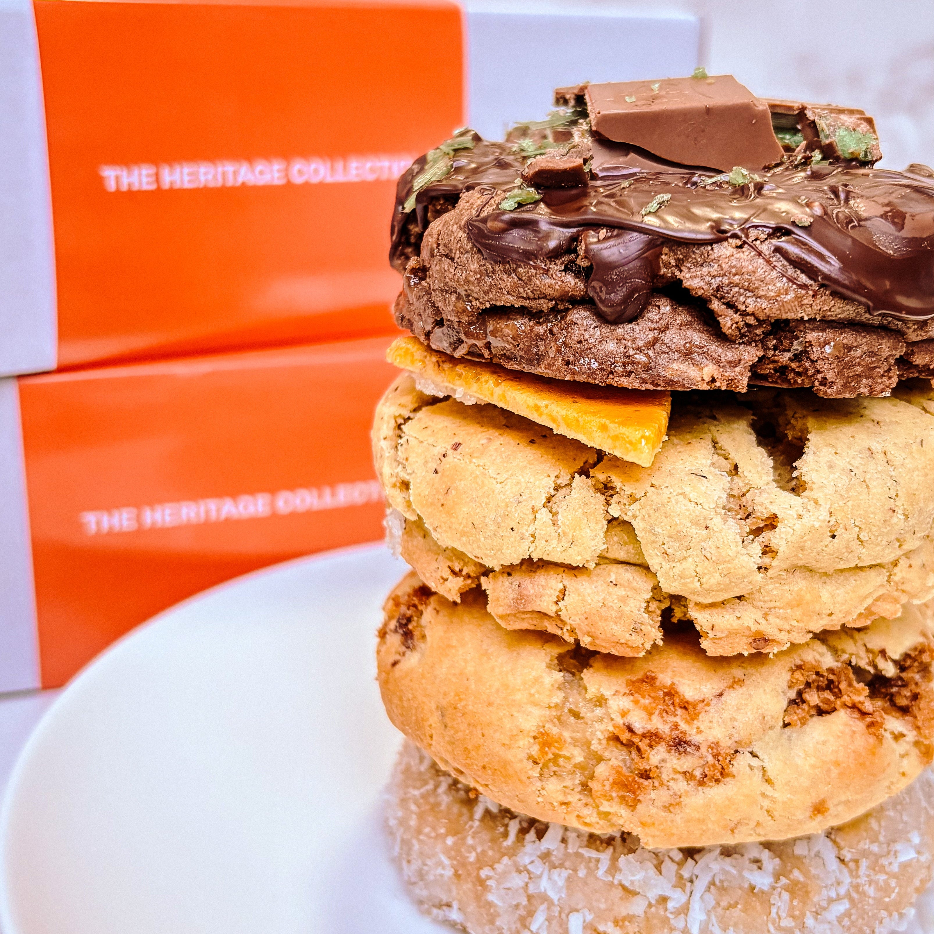 Stack of layered cookies with chocolate and peanut butter on a white plate, with an orange box in the background.